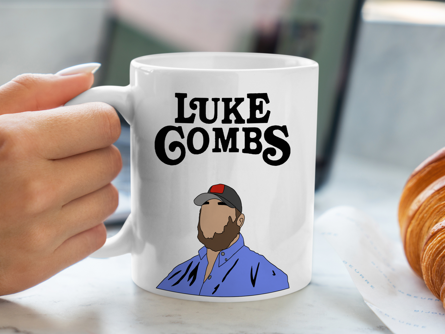 A white ceramic mug with a drawing of a Luke Combs, above it is the text Luke Combs on the front. This is a 10oz mug which is perfect for fans of Luke Combs. Made and sold by Krissi's Creations.