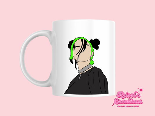 A white ceramic mug with a drawing of Billie Eilish with her Green and black hair on the front. This is a 10oz mug which is perfect for fans of Billie Eilish, particularly her Concerts. Made and sold by Krissi's Creations.