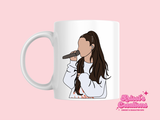 A white ceramic mug with a drawing of Ariana Grande on the front. This is a 10oz mug which is perfect for fans of Ariana Grande Concerts. Made and sold by Krissi's Creations.