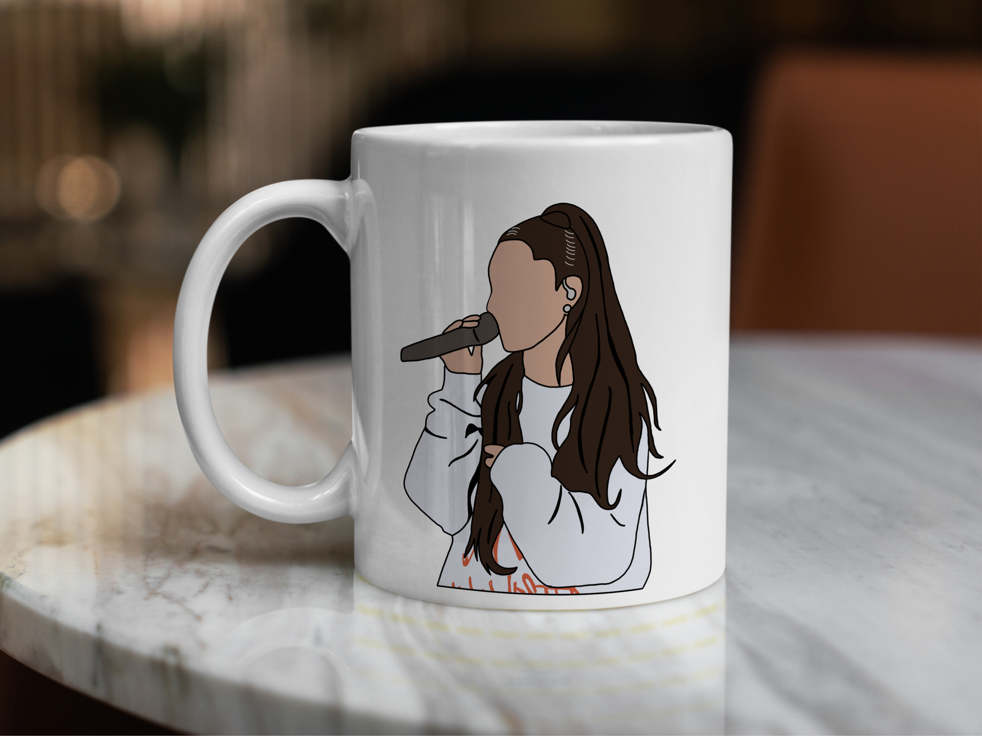 A white ceramic mug with a drawing of Ariana Grande on the front. This is a 10oz mug which is perfect for fans of Ariana Grande Concerts. Made and sold by Krissi's Creations.