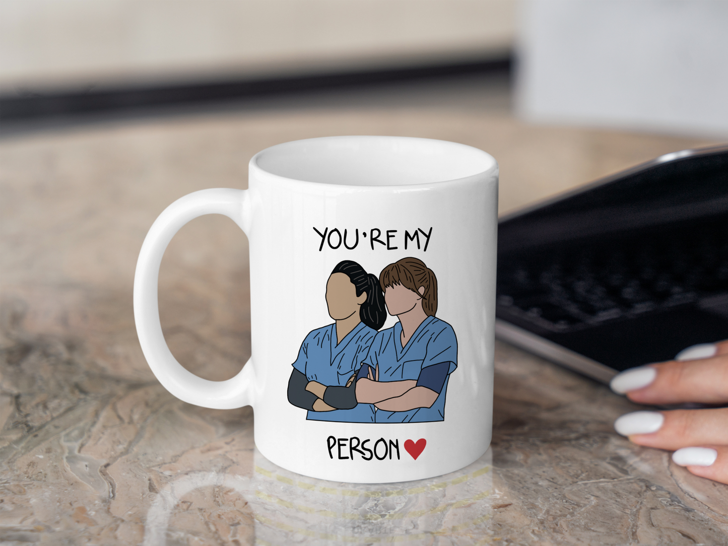 A white ceramic mug with a drawing of Meredith Grey and Cristina Yang from Grey's Anatomy on the front with the text You're my person. This is a 10oz mug which is perfect for fans of Grey's Anatomy, particularly the characters Meredith Grey and Cristina Yang. Made and sold by Krissi's Creations.