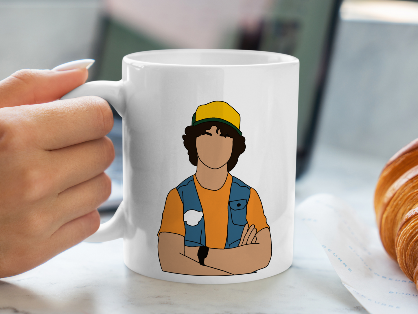 A white ceramic mug with a drawing of Dustin Henderson from Stranger Things on the front. This is a 10oz mug which is perfect for fans of Stranger Things, particularly the character Dustin Henderson. Made and sold by Krissi's Creations.