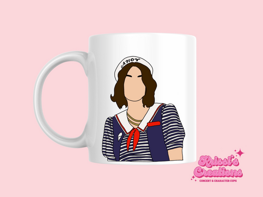 A white ceramic mug with a drawing of Robin Buckley from Stranger Things on the front. This is a 10oz mug which is perfect for fans of Stranger Things, particularly the character Robin Buckley. Made and sold by Krissi's Creations.
